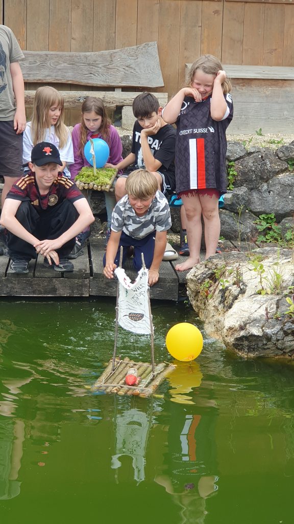 Kinder bauen selbst ein Floss und testen es im Wasser, Abenteuerlager Dakawo Schweiz